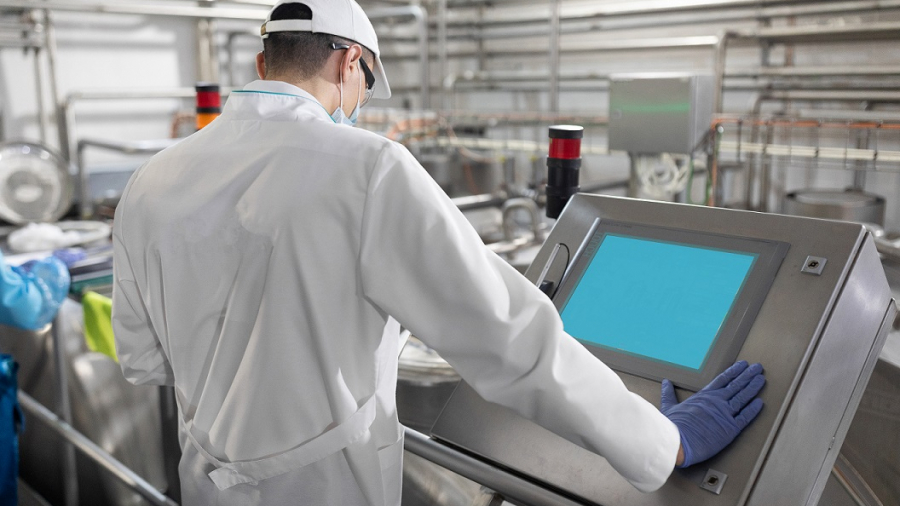 concentrated technologist taking necessary notes with help of digital tablet while standing at production department of dairy factory. The inspector carries out control at the cheese factory