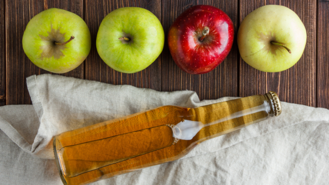 Green apples with red one and apple juice top view on a cloth and wooden background